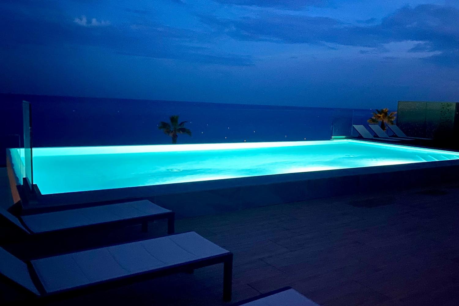Shared pool at night with sea view